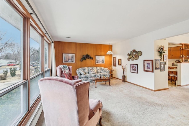 living area featuring light carpet, wood walls, and baseboards