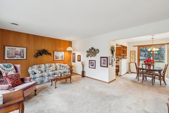 living room with wooden walls, baseboards, visible vents, carpet flooring, and a notable chandelier