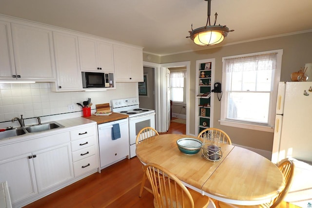 kitchen featuring dark wood-style floors, ornamental molding, white cabinetry, a sink, and white appliances