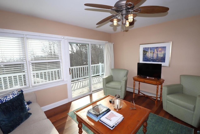 living area featuring a baseboard radiator, ceiling fan, baseboards, and wood finished floors