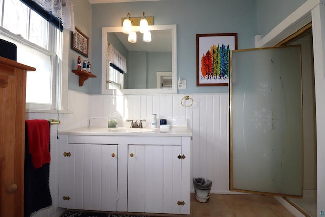 full bath featuring a wainscoted wall, a stall shower, vanity, and tile patterned floors