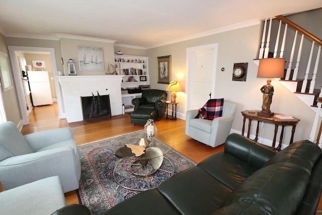 living room featuring crown molding, a fireplace, wood finished floors, baseboards, and stairs