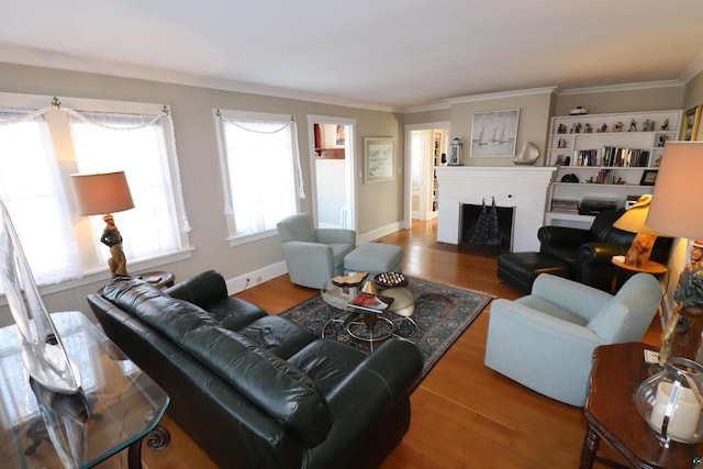 living room with crown molding, a fireplace, baseboards, and wood finished floors