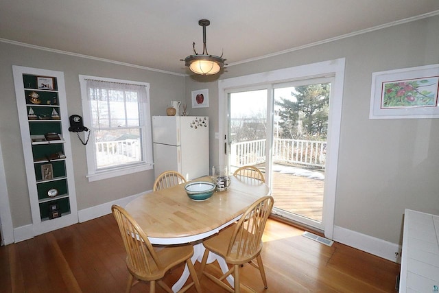 dining space with visible vents, crown molding, baseboards, and wood finished floors