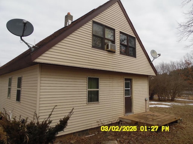 view of side of property featuring a chimney and cooling unit