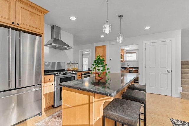 704 Fromm Ln, Elkhart Lake, WI 53020 - kitchen with appliances with stainless steel finishes, wall chimney range hood, a kitchen breakfast bar, a center island, and light wood-style floors