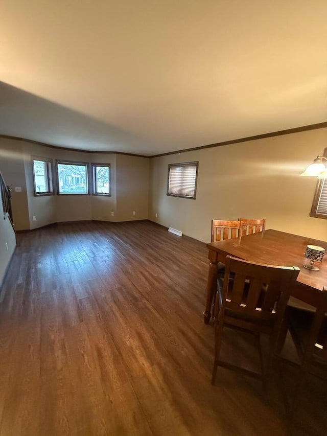 unfurnished dining area featuring visible vents, baseboards, wood finished floors, and crown molding