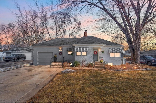 view of front of home with concrete driveway, a chimney, an attached garage, and stucco siding