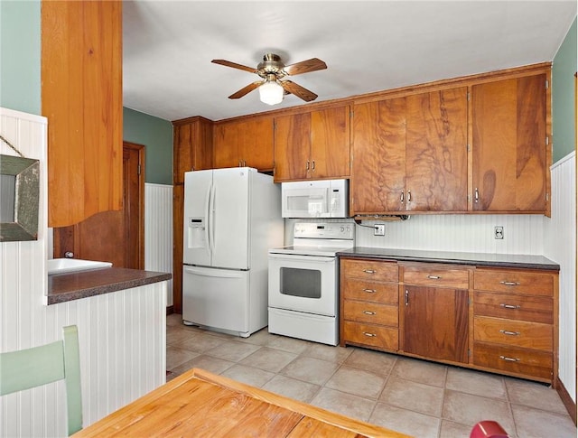 kitchen with white appliances, light tile patterned floors, brown cabinetry, and a ceiling fan