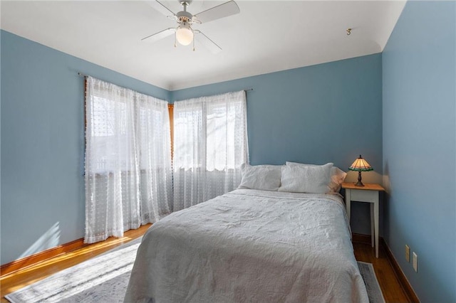 bedroom with ceiling fan, wood finished floors, and baseboards