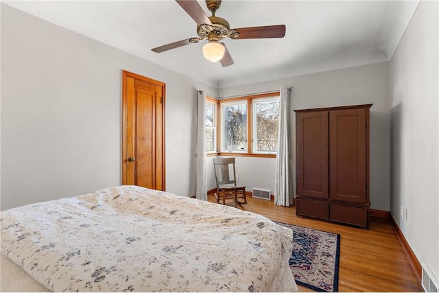 bedroom with light wood-style floors, baseboards, visible vents, and ceiling fan