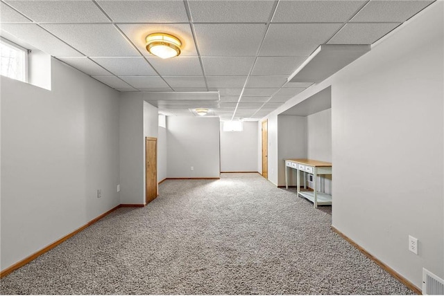 below grade area featuring carpet floors, a paneled ceiling, visible vents, and baseboards