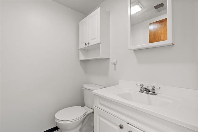 half bathroom featuring visible vents, vanity, and toilet