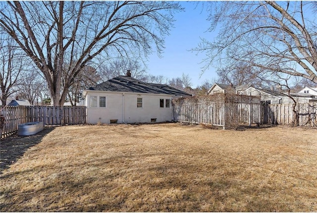 rear view of property featuring crawl space, a fenced backyard, a yard, and stucco siding