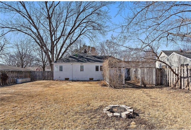 back of house with an outdoor fire pit, a fenced backyard, crawl space, a lawn, and stucco siding