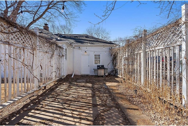 view of side of property featuring fence, a chimney, and stucco siding