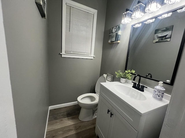 bathroom featuring toilet, vanity, baseboards, and wood finished floors