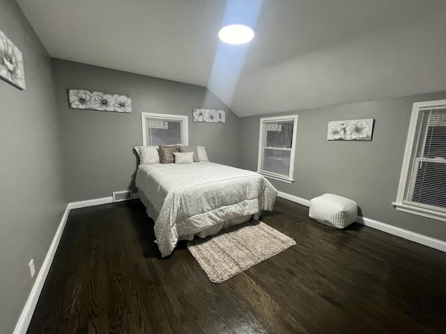 bedroom with lofted ceiling, visible vents, baseboards, and wood finished floors