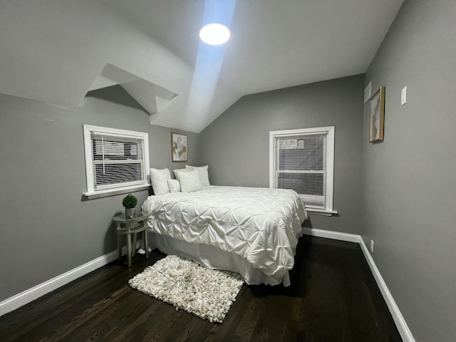 bedroom featuring lofted ceiling, baseboards, and wood finished floors