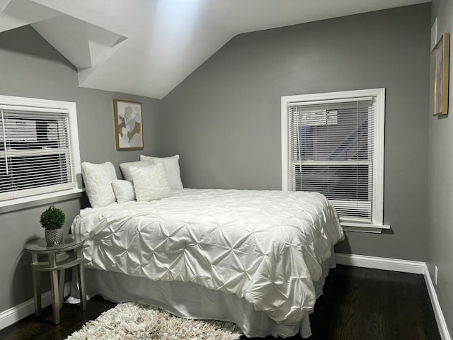 bedroom with vaulted ceiling, wood finished floors, and baseboards