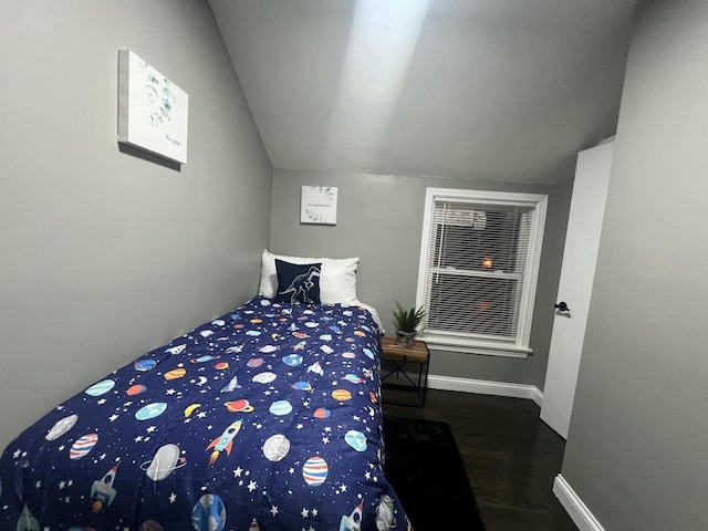 bedroom with vaulted ceiling, wood finished floors, and baseboards