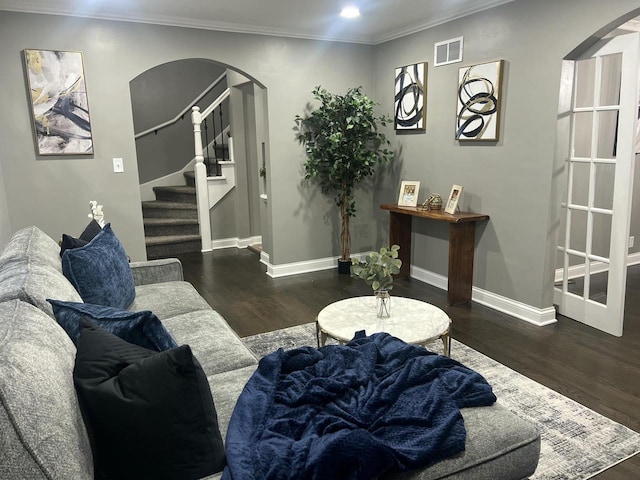 living room featuring baseboards, arched walkways, visible vents, wood finished floors, and crown molding