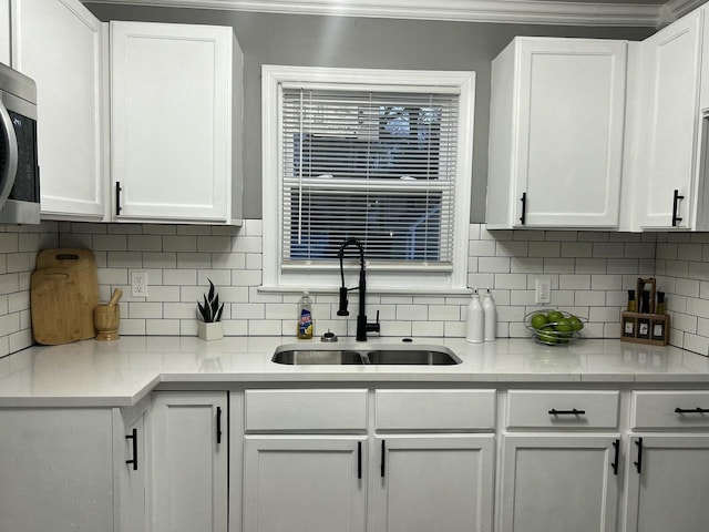 kitchen featuring light countertops, a sink, and white cabinetry