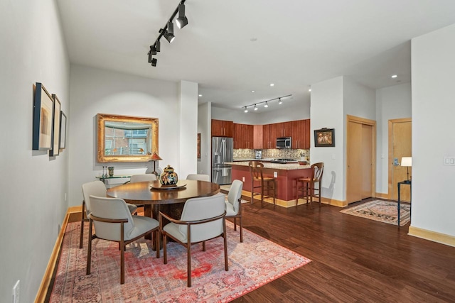 dining area with track lighting, wood finished floors, and baseboards