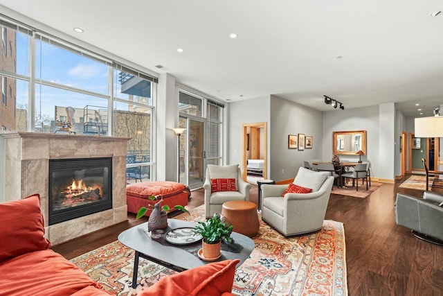 living area with a high end fireplace, rail lighting, baseboards, and wood finished floors