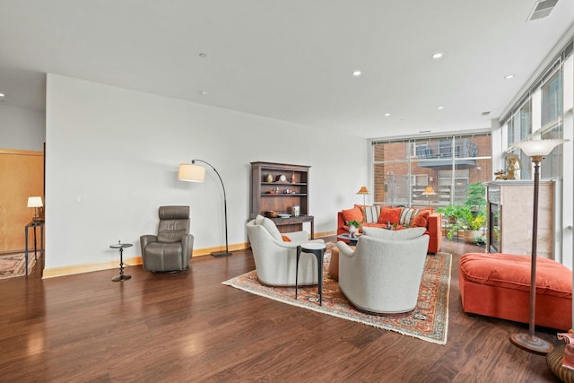 living area with baseboards, visible vents, floor to ceiling windows, and wood finished floors