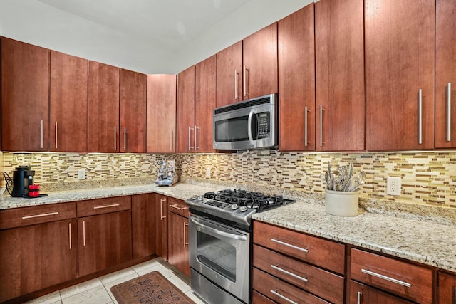 kitchen with stainless steel appliances, backsplash, light stone counters, and light tile patterned floors