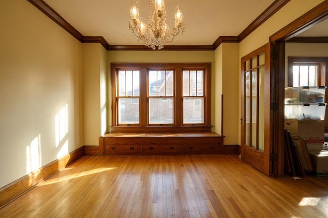 interior space with baseboards, ornamental molding, light wood-style flooring, and a notable chandelier