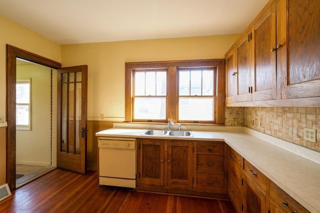 kitchen featuring dishwasher, dark wood-style flooring, a sink, and brown cabinetry