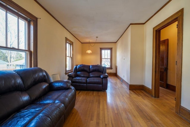 living room with light wood-type flooring, crown molding, and baseboards