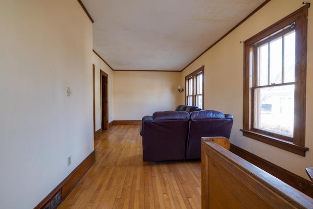 living room featuring ornamental molding, a healthy amount of sunlight, light wood-style flooring, and baseboards