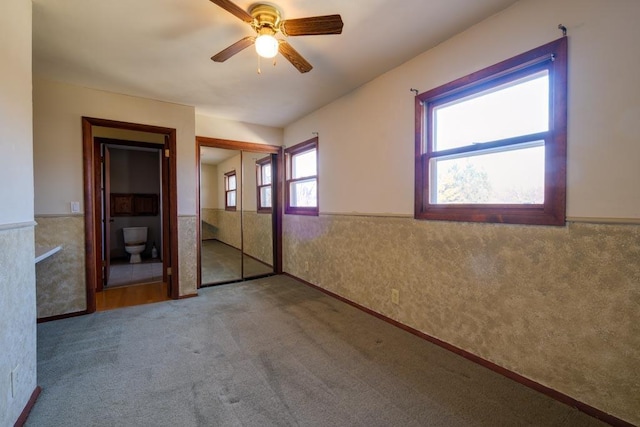 unfurnished bedroom with carpet, a wainscoted wall, and ceiling fan