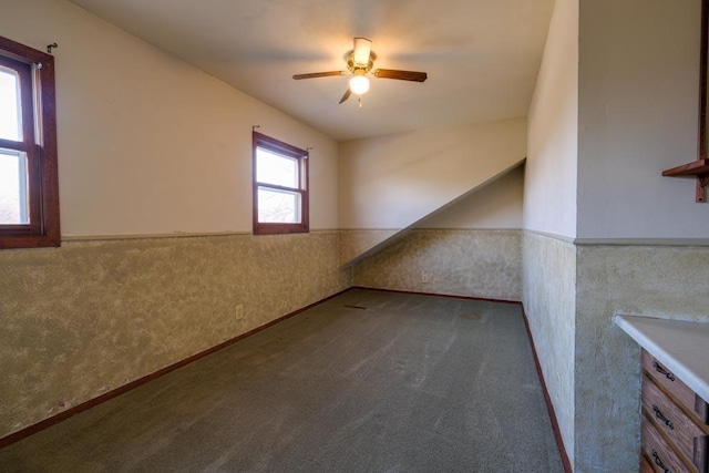 additional living space featuring wainscoting, carpet flooring, and a ceiling fan