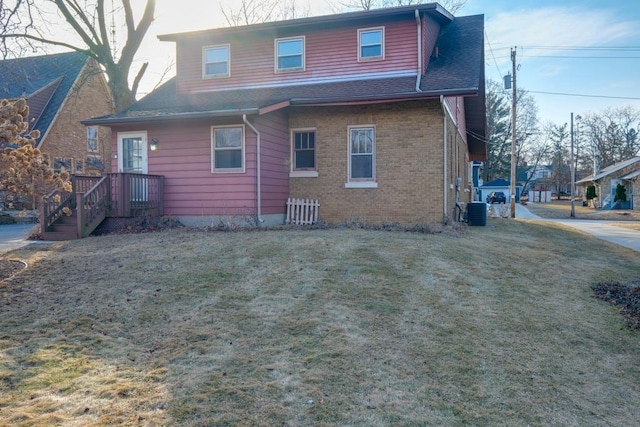 rear view of property with brick siding, a lawn, a shingled roof, and cooling unit