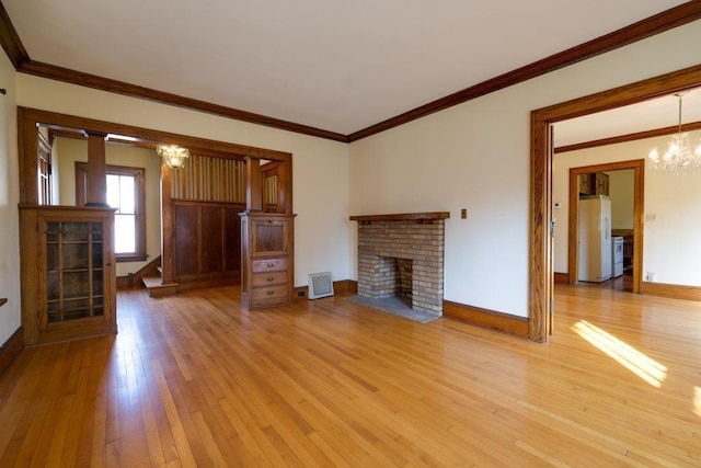 unfurnished living room featuring an inviting chandelier, light wood-style flooring, a fireplace, and baseboards