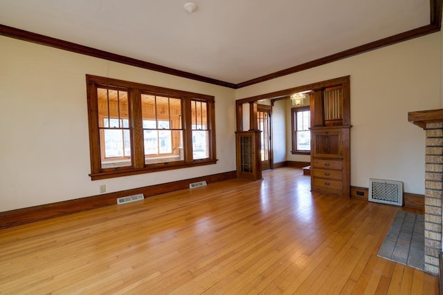 unfurnished living room with ornamental molding, visible vents, light wood-style flooring, and baseboards