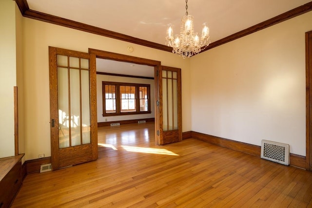 unfurnished room featuring light wood finished floors, baseboards, visible vents, and crown molding