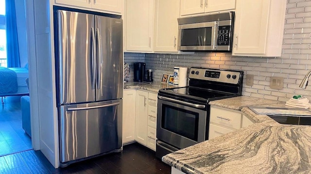 kitchen featuring appliances with stainless steel finishes, white cabinetry, and light stone counters