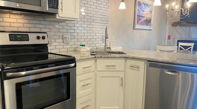 kitchen featuring light stone counters, stainless steel appliances, a sink, white cabinets, and tasteful backsplash