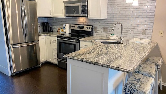 kitchen with white cabinets, tasteful backsplash, stainless steel appliances, and a sink