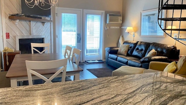 living area featuring an AC wall unit, a notable chandelier, a fireplace, and wood finished floors