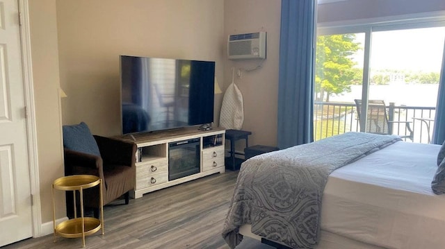 bedroom with access to outside, a wall mounted AC, and wood finished floors