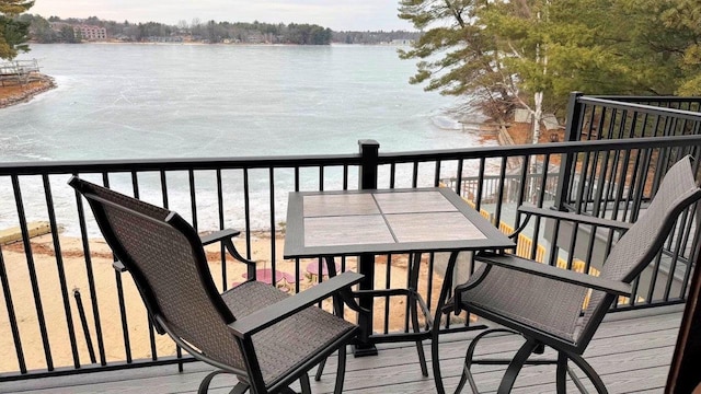 balcony with outdoor dining space and a water view