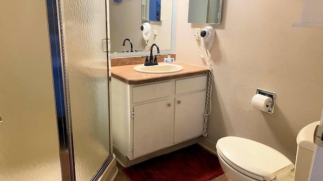 full bathroom featuring a stall shower, a textured wall, vanity, and toilet