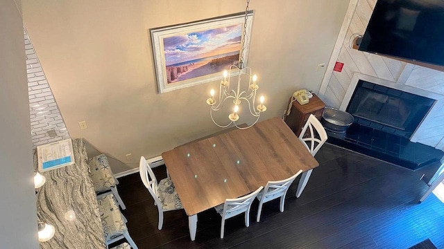 dining area featuring a fireplace, a chandelier, and wood finished floors