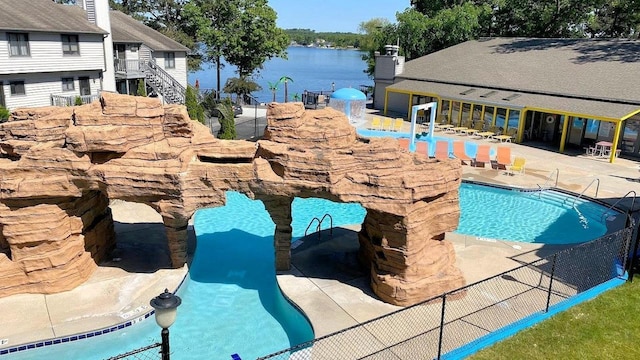 community pool with a water view, fence, and a patio